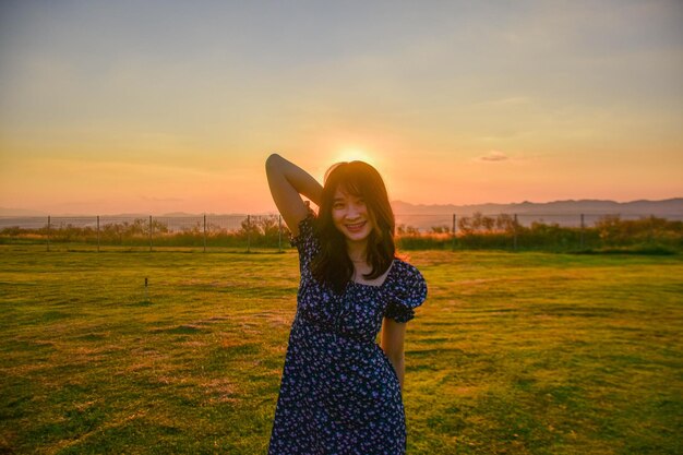 Foto vista traseira de uma mulher de pé no campo contra o céu durante o pôr do sol