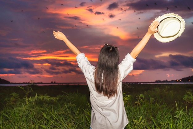 Foto vista traseira de uma mulher de pé no campo contra o céu durante o pôr do sol