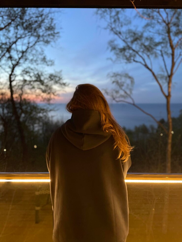Foto vista traseira de uma mulher de pé por uma árvore nua contra o céu