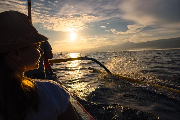 Foto vista traseira de uma mulher em um navio náutico durante o pôr-do-sol