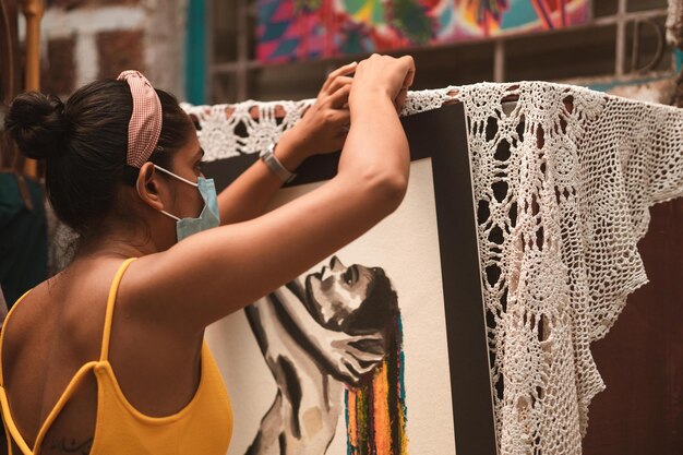 Vista traseira de uma mulher exibindo suas obras de arte durante a pandemia de COVID-19