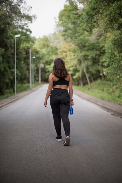 Vista traseira de uma mulher fazendo esporte na estrada