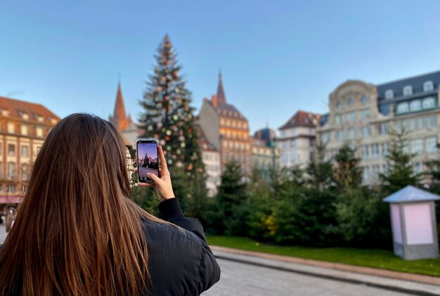 Vista traseira de uma mulher fotografando contra o céu durante o pôr do sol