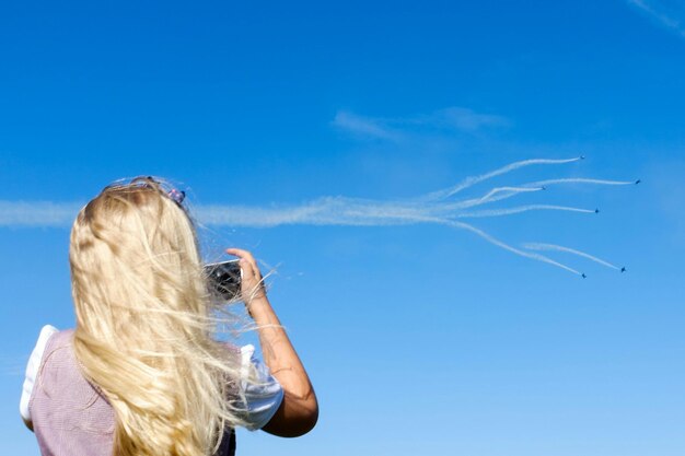 Foto vista traseira de uma mulher fotografando um espetáculo aéreo