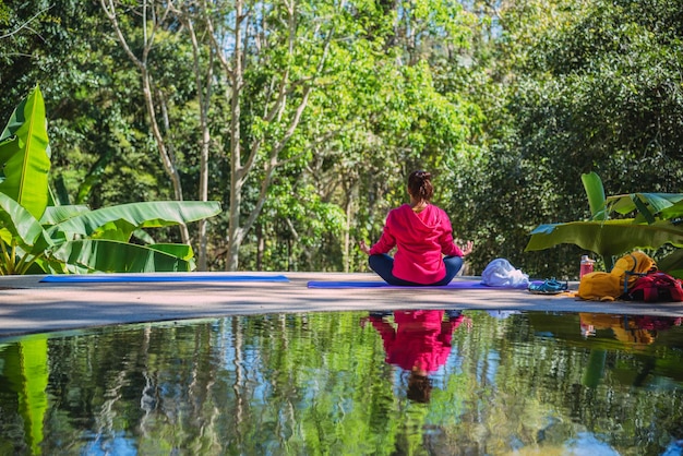 Foto vista traseira de uma mulher meditando contra as plantas