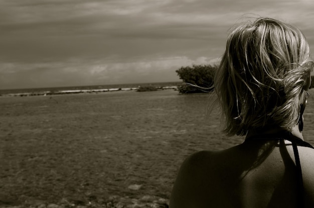 Foto vista traseira de uma mulher na costa do mar contra o céu