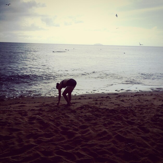 Foto vista traseira de uma mulher na costa na praia contra o céu durante o pôr do sol