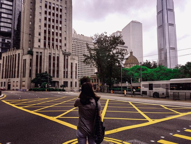 Foto vista traseira de uma mulher na estrada contra edifícios na cidade
