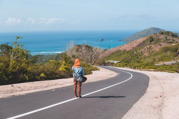 Foto vista traseira de uma mulher na estrada pelo mar contra o céu