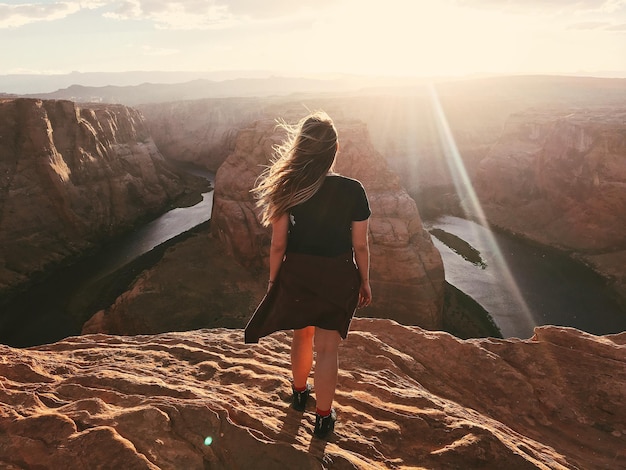 Foto vista traseira de uma mulher na montanha durante o pôr-do-sol