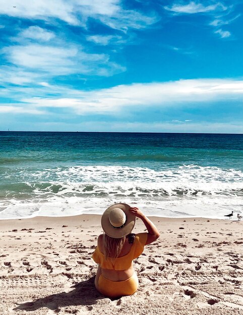 Foto vista traseira de uma mulher na praia contra o céu