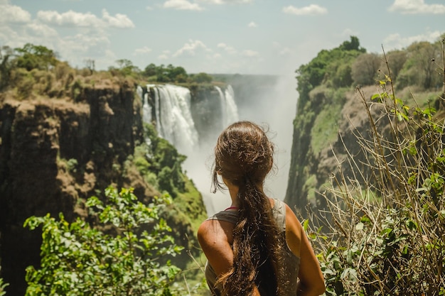 Foto vista traseira de uma mulher olhando para a cachoeira