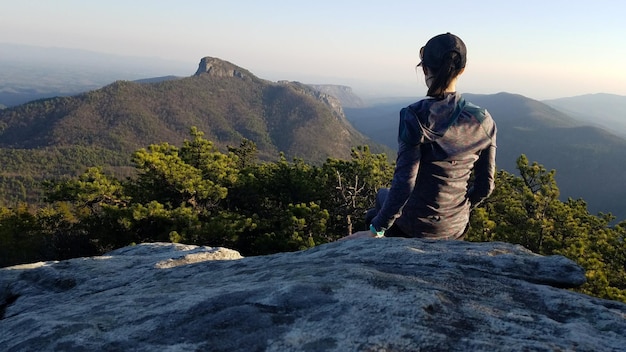 Foto vista traseira de uma mulher olhando para a vista da cordilheira contra o céu