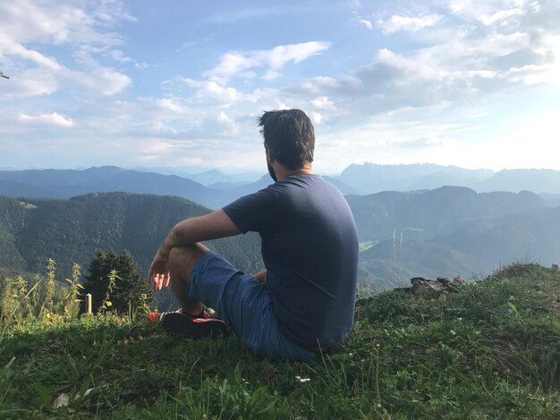 Vista traseira de uma mulher olhando para as montanhas contra o céu