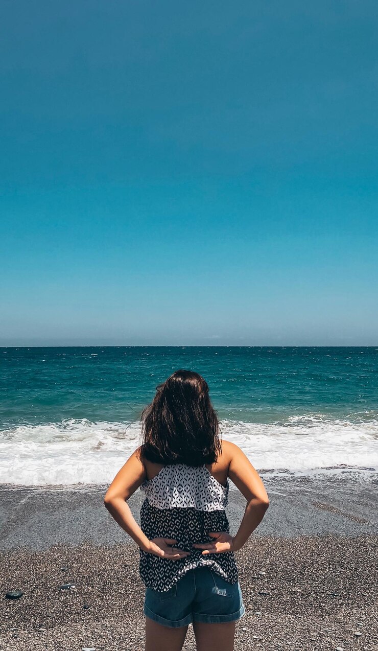 Foto vista traseira de uma mulher olhando para o mar contra o céu