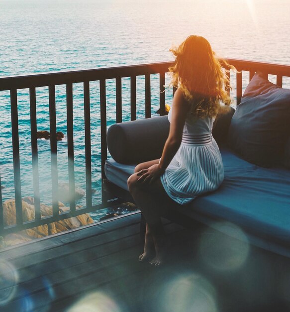 Foto vista traseira de uma mulher olhando para o mar durante o pôr do sol