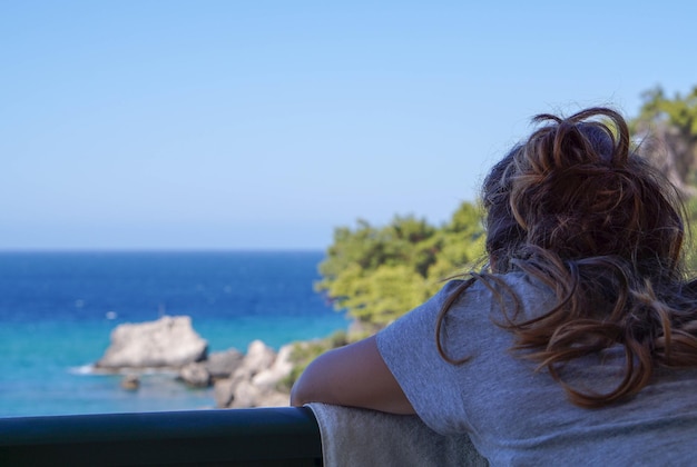 Vista traseira de uma mulher olhando para o mar