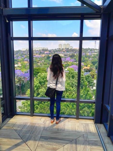 Foto vista traseira de uma mulher olhando pela janela