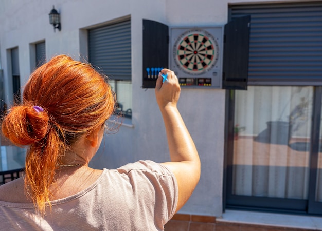 Vista traseira de uma mulher segurando uma câmera enquanto está de pé contra uma estrutura construída