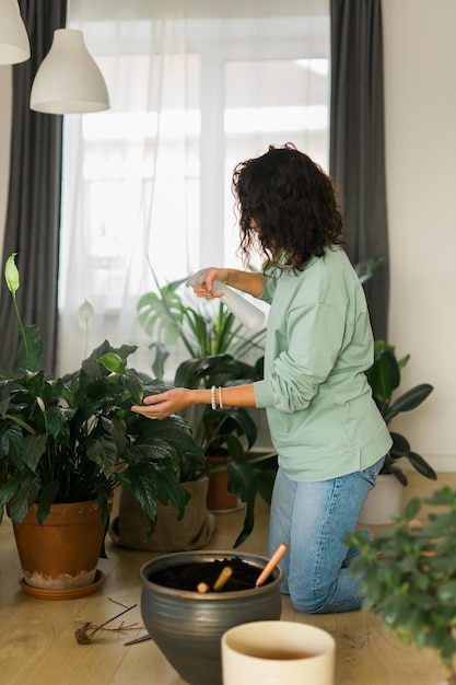 Foto vista traseira de uma mulher segurando uma planta em vaso em casa
