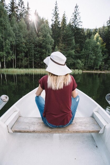 Foto vista traseira de uma mulher sentada em um barco no lago