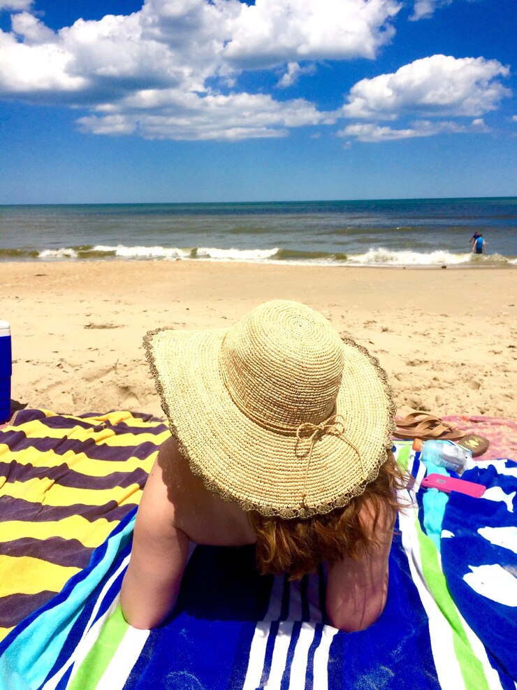 Foto vista traseira de uma mulher sentada na praia contra o céu