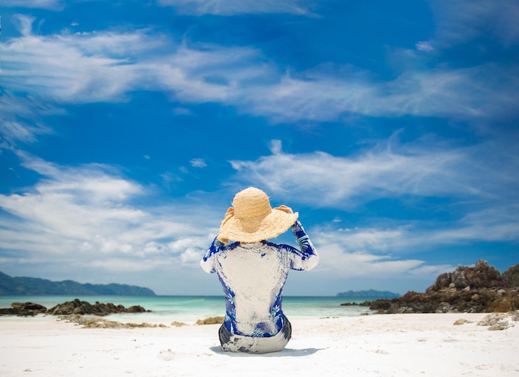 Foto vista traseira de uma mulher sentada na praia em um dia ensolarado