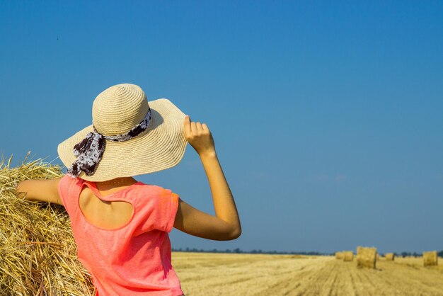 Foto vista traseira de uma mulher vestindo um chapéu no campo contra um céu claro