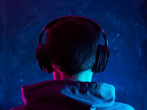Vista traseira de uma pessoa na luz de neon de fones de ouvido aéreos
