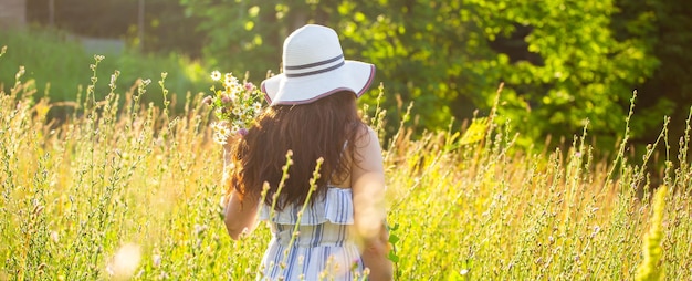 Vista traseira do banner da bela jovem caminhando entre flores silvestres no espaço ensolarado da cópia do dia de verão Conceito alegria de se comunicar com a natureza do verão