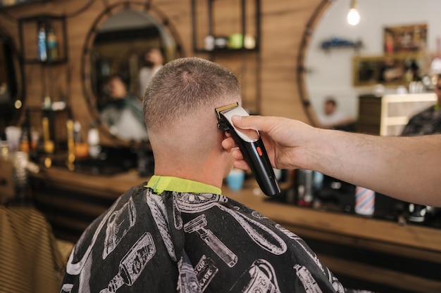 Vista traseira do cabeleireiro cortando o cabelo da barbearia do cliente masculino
