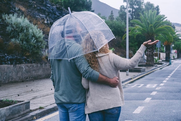 Vista traseira do casal feliz apaixonado aproveitando o dia de chuva com guarda-chuva Rua urbana em segundo plano Atividade de lazer ao ar livre e conceito de relacionamento juntos para sempre Mau tempo dia de inverno Pessoas