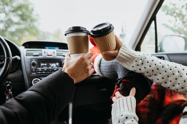 Vista traseira do casal tomando café juntos no carro