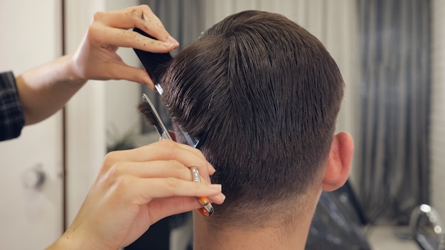 Vista traseira do corte de cabelo do barbeiro feminino, fazendo o