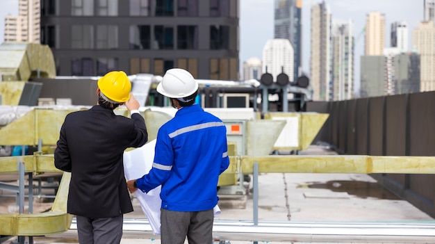 Vista traseira do empresário e proprietário do prédio de escritórios e engenheiro de energia planejam um projeto para construir um painel solar para o edifício em construção conceito de energia alternativa limpa e verde