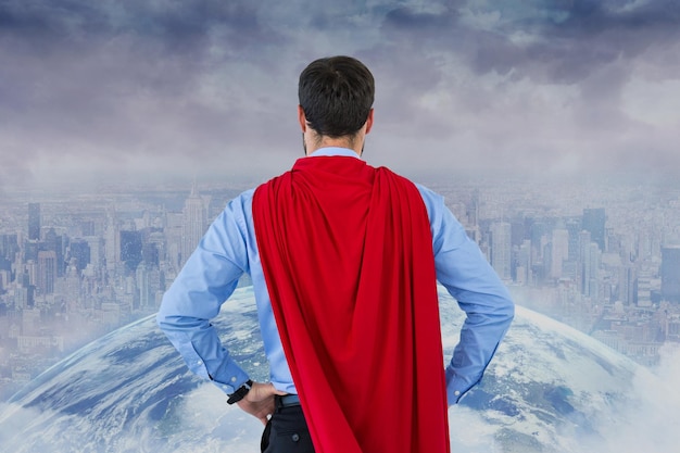 Foto vista traseira do empresário vestindo capa de super-herói enquanto olha para a cidade e o globo