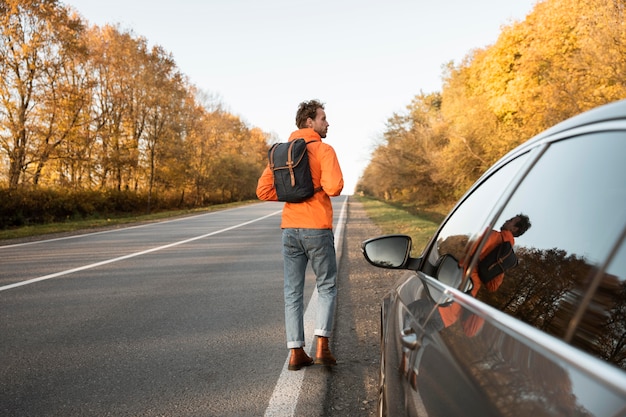 Vista traseira do homem ao lado do carro durante uma viagem