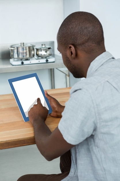 Vista traseira do homem usando tablet digital na cozinha em casa