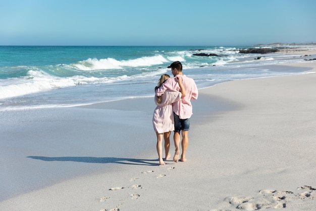 Vista traseira do jovem casal abraçando na praia