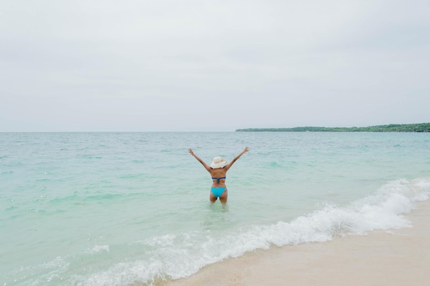 Foto vista traseira do jovem em traje de banho com os braços estendidos mar caribenho colombiano de cartagena