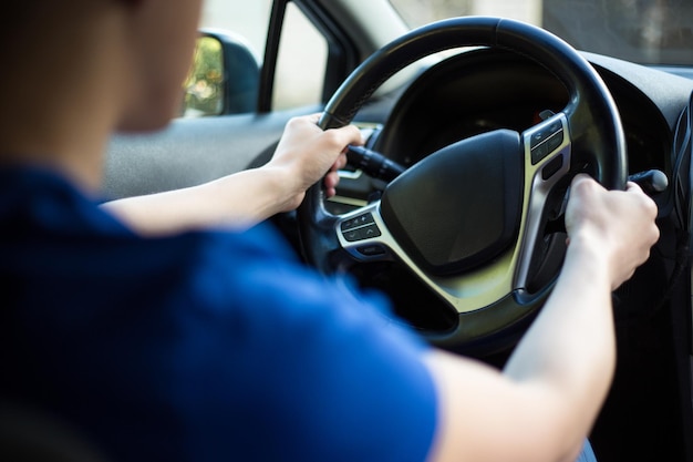 Vista traseira do jovem motorista masculino segurando o volante