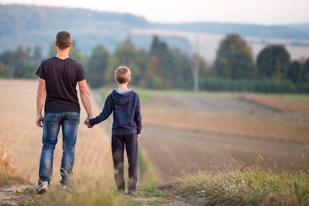 Vista traseira do jovem pai e filho caminhando juntos