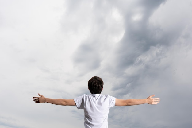 Vista traseira do menino olhando para o céu tempestuoso