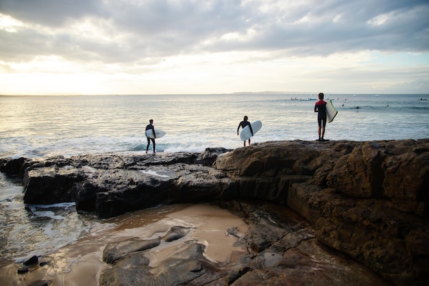 Vista traseira do pai e filhos em pé na prancha de surf Rock Whit antes de saltar para o conceito WaterFamily