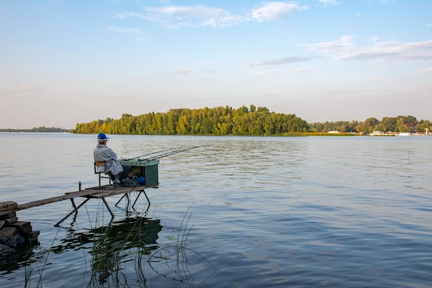 Vista traseira do pescador com muitas varas de pesca e uma rede para peixes Pesca no rio