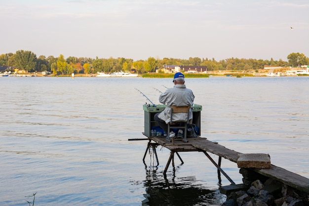 Vista traseira do pescador com muitas varas de pesca e uma rede para peixes Pesca no rio