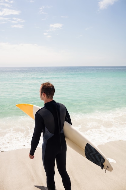 Vista traseira do surfista com pé de prancha de surf na praia