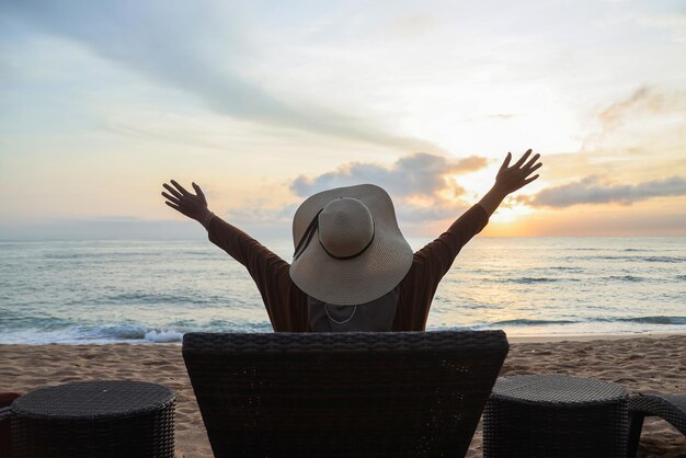 Vista traseira do turista feminino sentado apreciando a vista à noite na praia