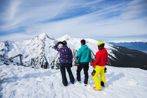 Vista traseira dos jovens desfrutando no inverno nevado no topo da montanha