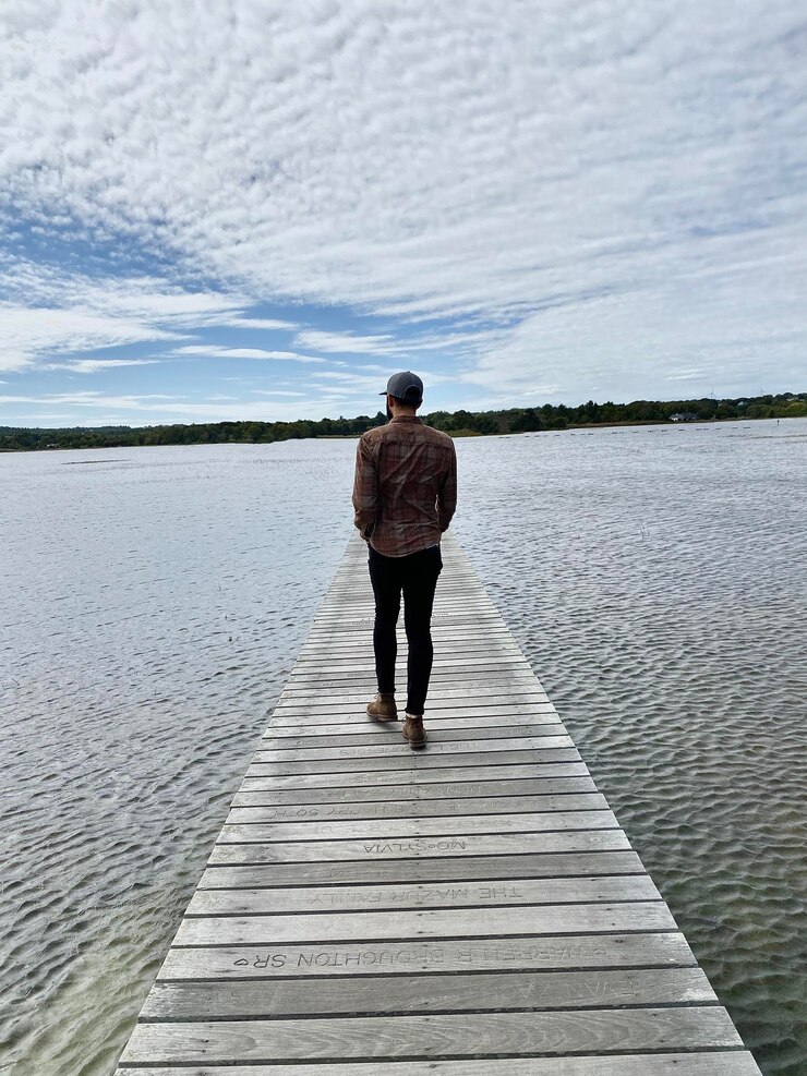 Foto vista traseira em todo o comprimento de um homem caminhando no meio do lago no cais